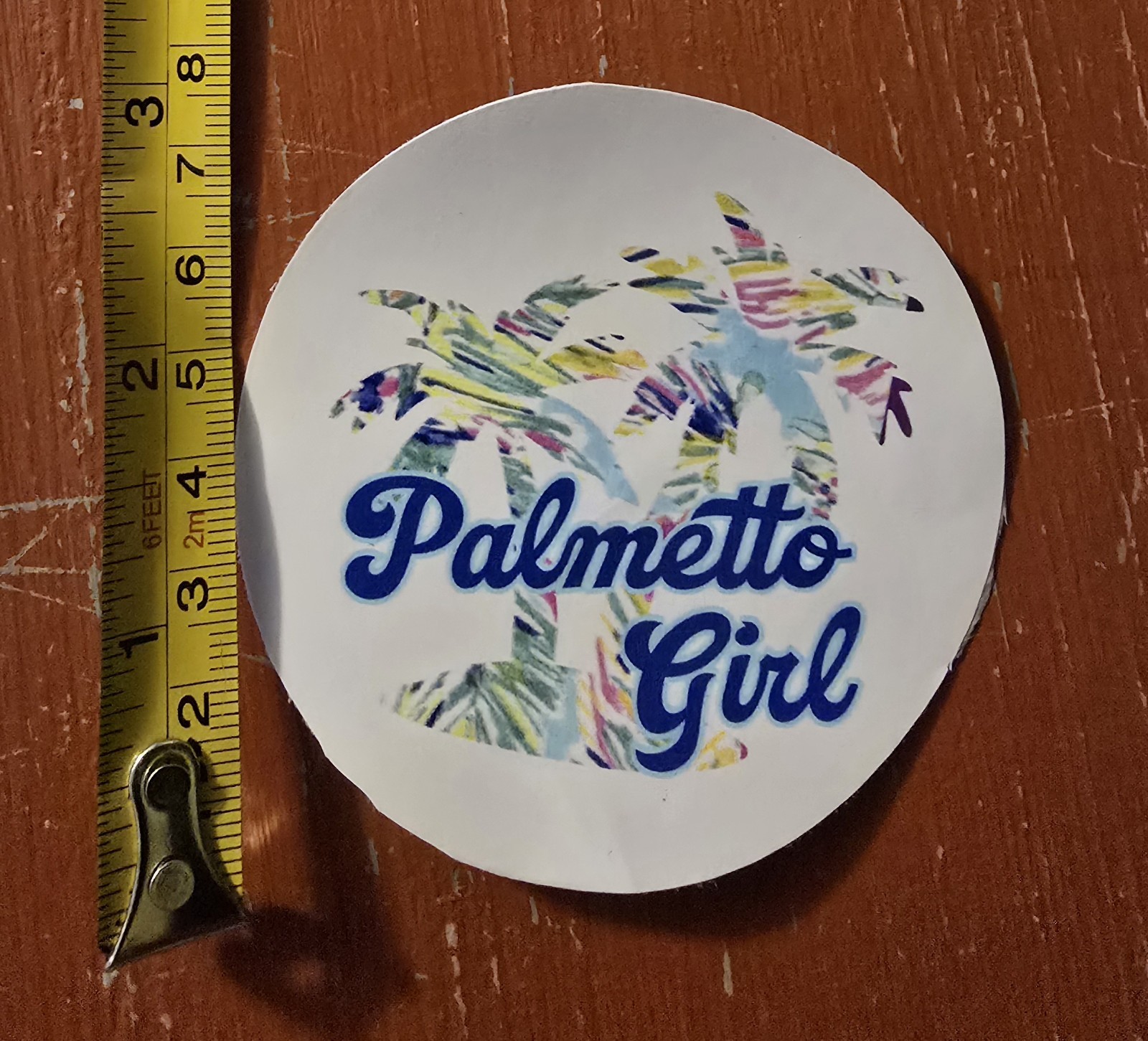 'Palmetto Girl' text and a colorful palm trees background design. 3in Sticker